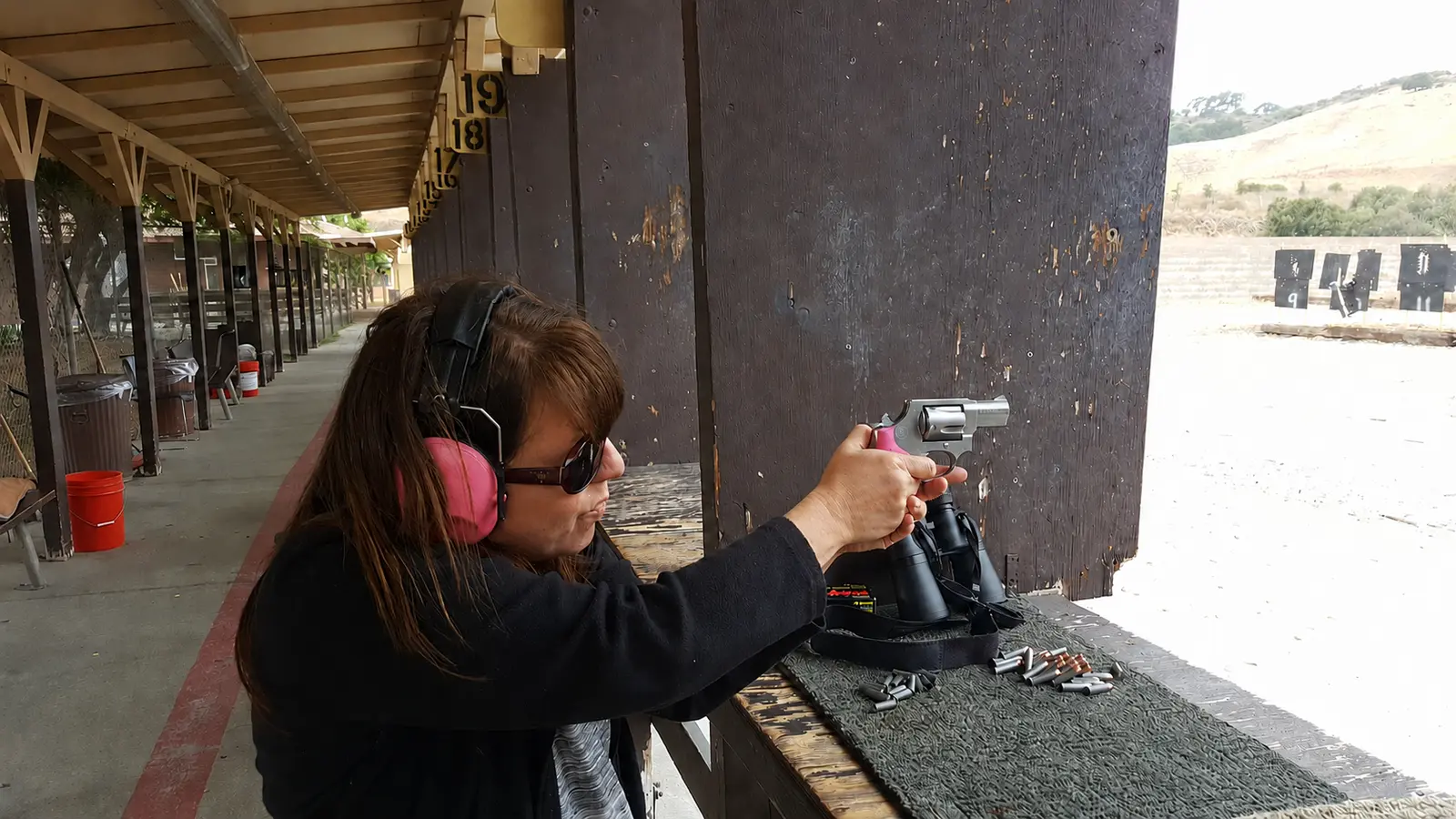Right-handed, left-eye-dominant woman shooting a .38 Special revolver at an outdoor range
