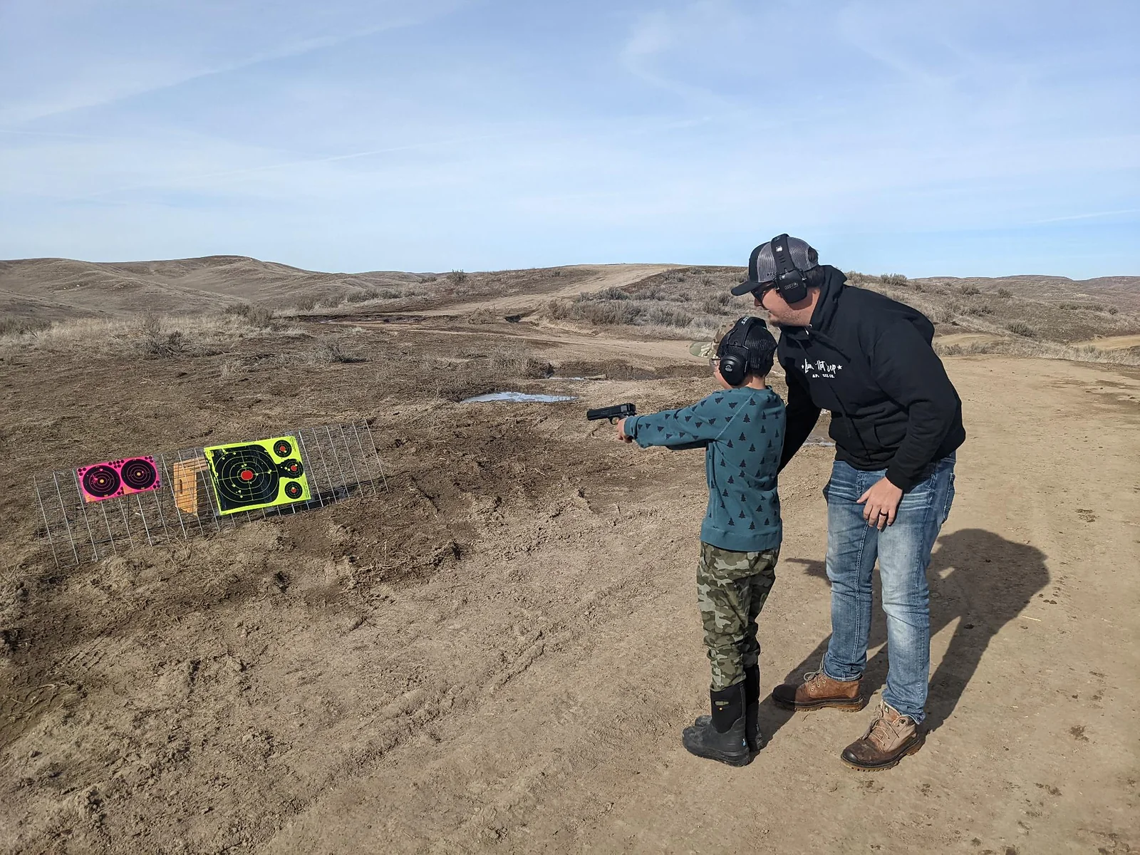 Instructor providing one-on-one handgun coaching at an outdoor range